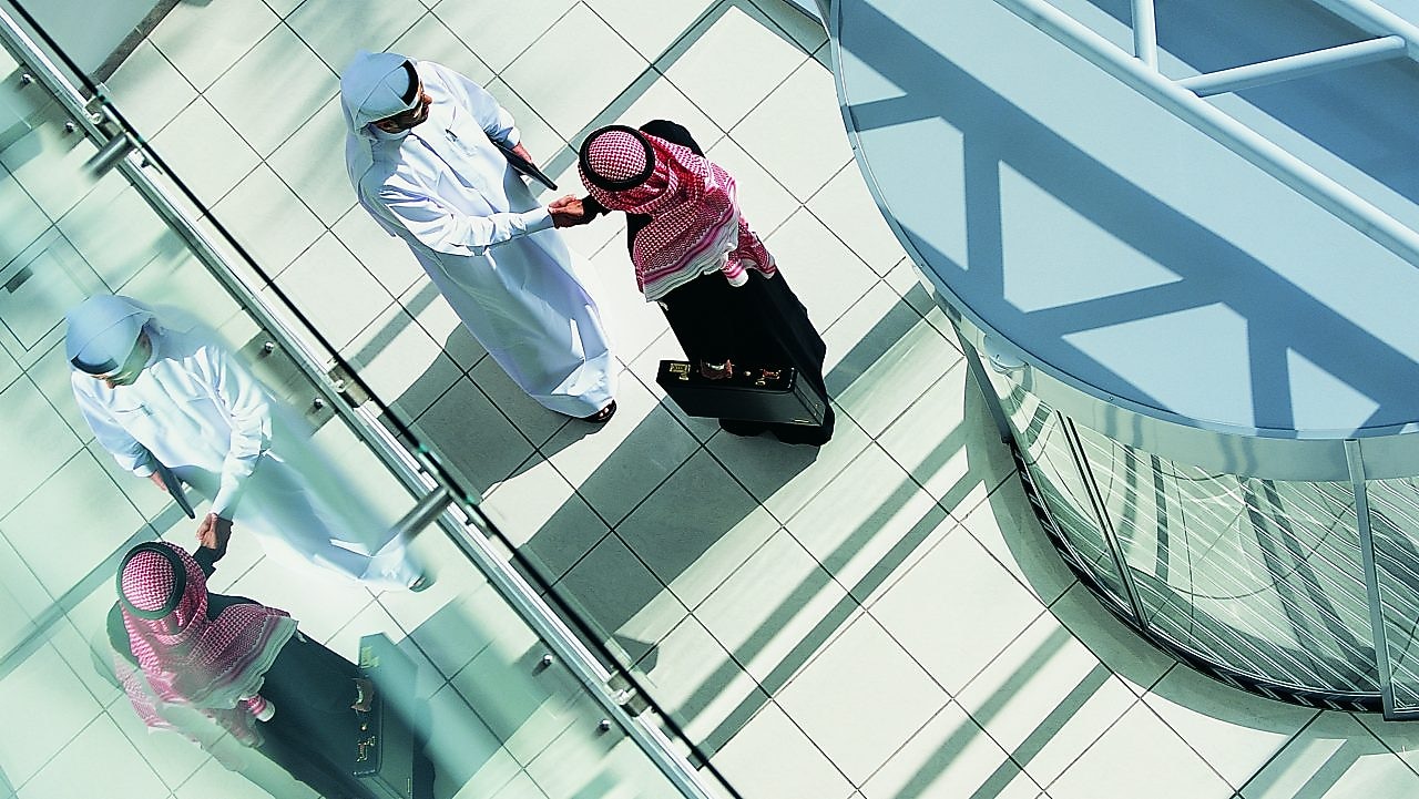 Overhead View of Two Businessmen Shaking Hands in a Lobby By a Revolving Door