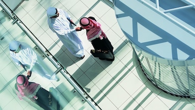 Overhead View of Two Businessmen Shaking Hands in a Lobby By a Revolving Door