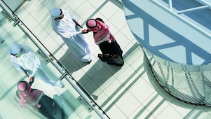Overhead View of Two Businessmen Shaking Hands in a Lobby By a Revolving Door