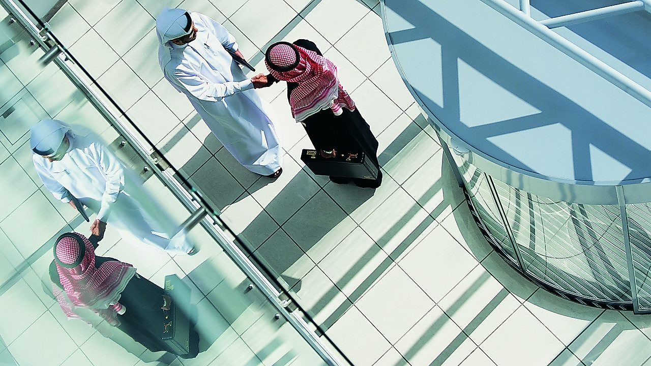 Overhead View of Two Businessmen Shaking Hands in a Lobby By a Revolving Door