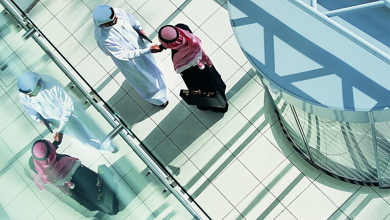 Overhead View of Two Businessmen Shaking Hands in a Lobby By a Revolving Door