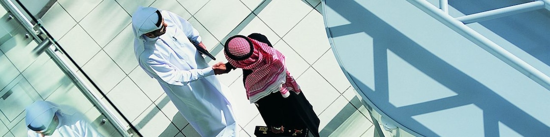 Overhead View of Two Businessmen Shaking Hands in a Lobby By a Revolving Door