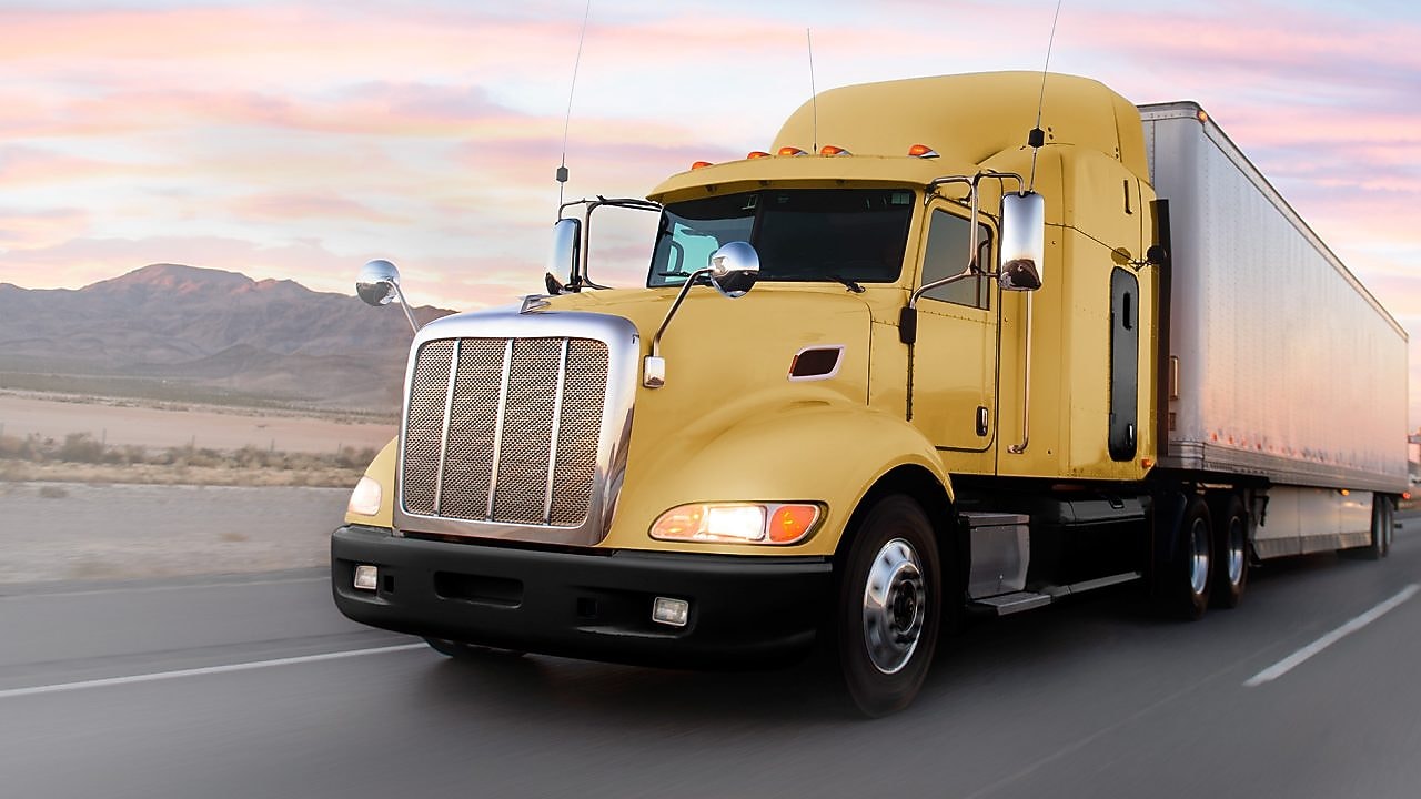 a yellow truck driving down a road at dusk