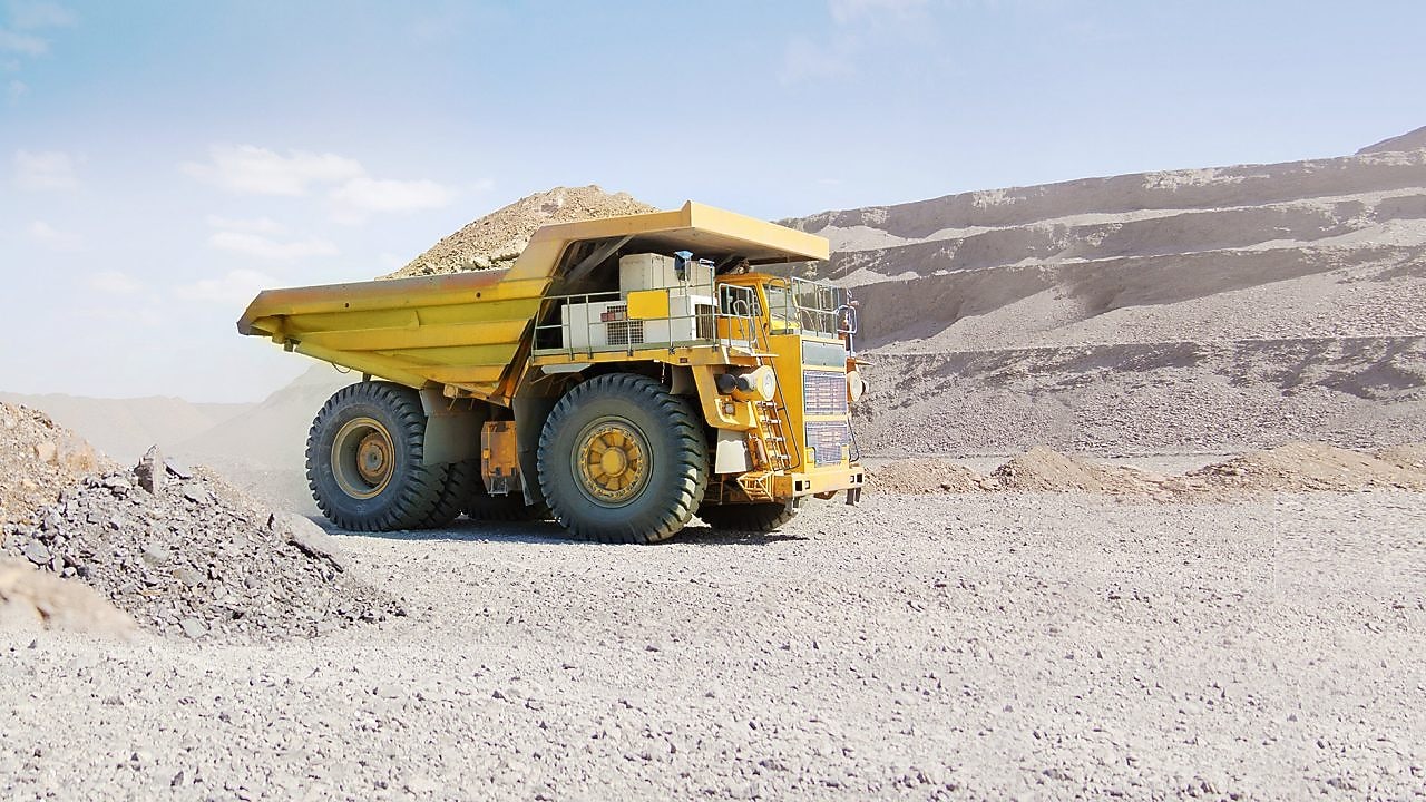 yellow dumper truck driving through gravel