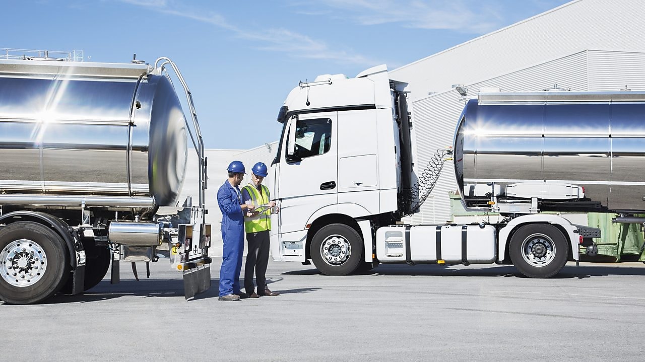 two technicians between two heavy oil trucks
