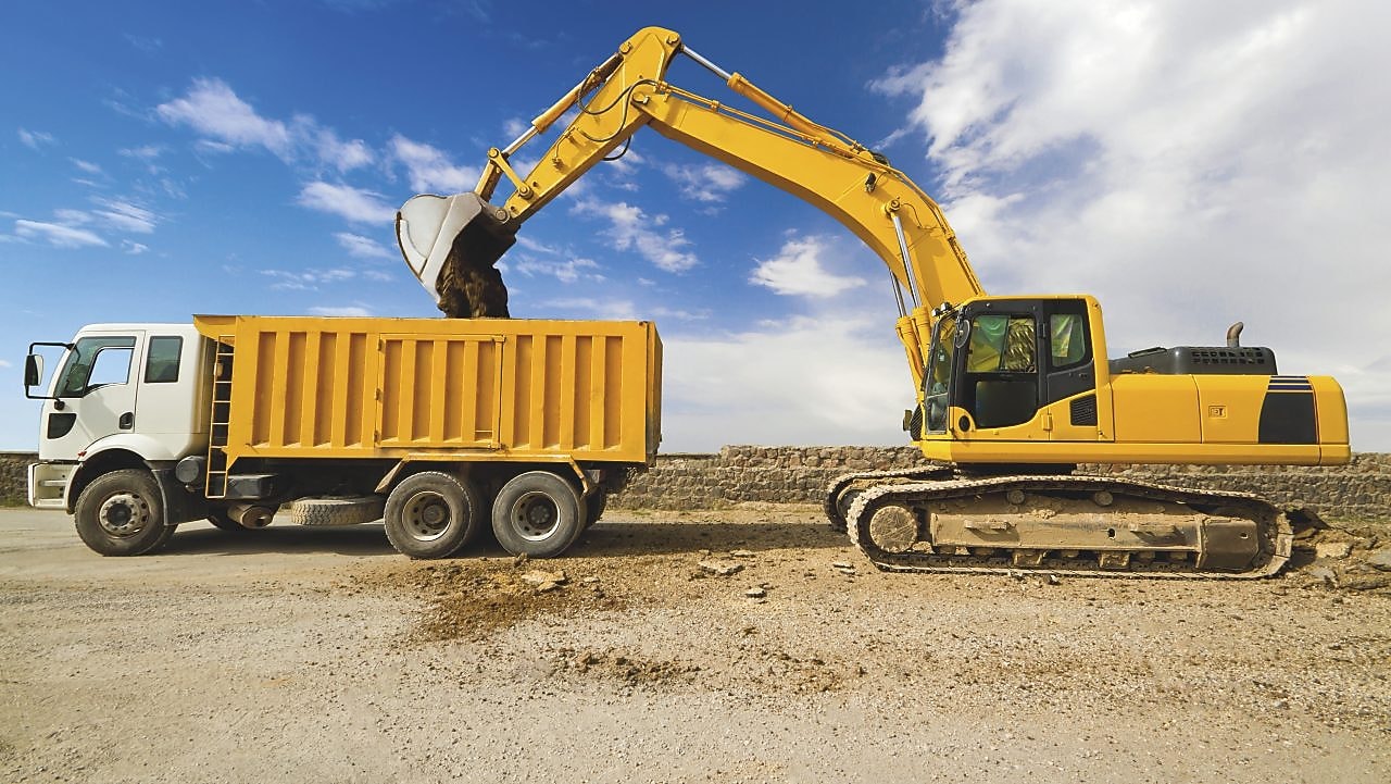 yellow excavator loading mud into a truck