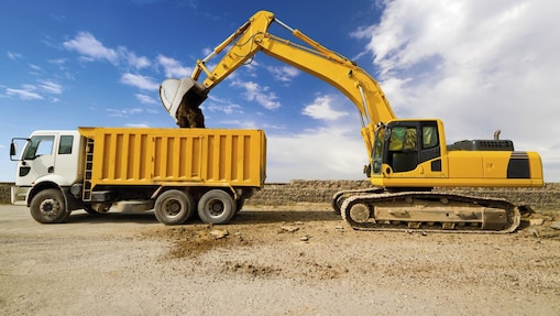 yellow excavator loading mud into a truck