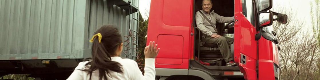 Man in red truck cab with door open waving to his daughter