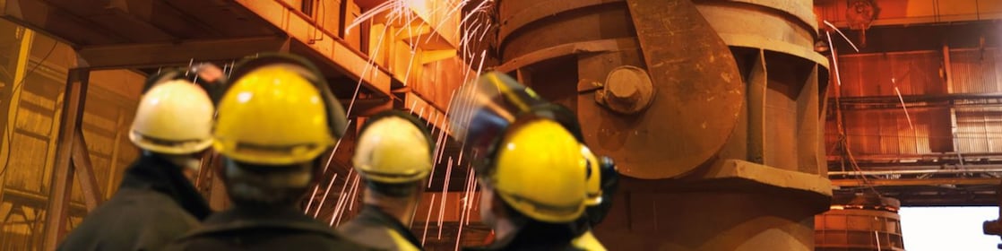 workers watching heavy machinery in a metal processing plant