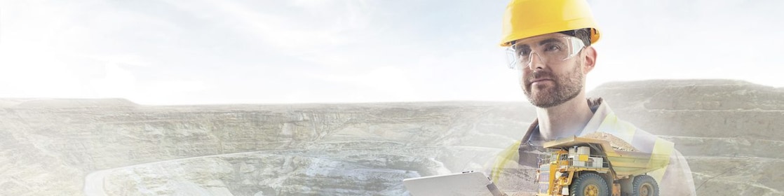 worker in yellow hard hat transposed onto a background of cliffs and a large yellow truck