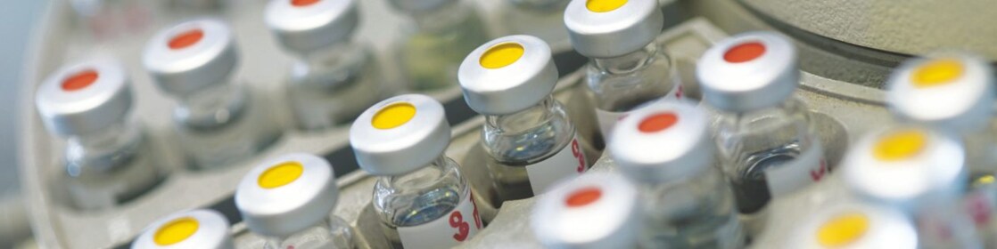 Rows of medicine vials sitting in a holder, some with red dots on the lid, and some with yellow dots on the lid