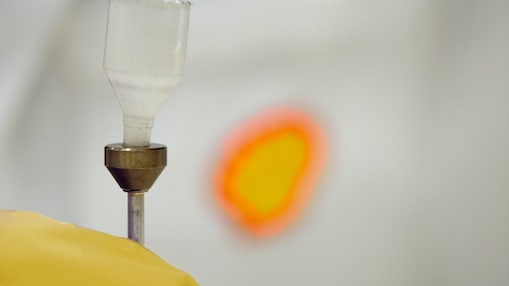 Liquid being poured into a plastic funnel by a shell scientist in a laboratory