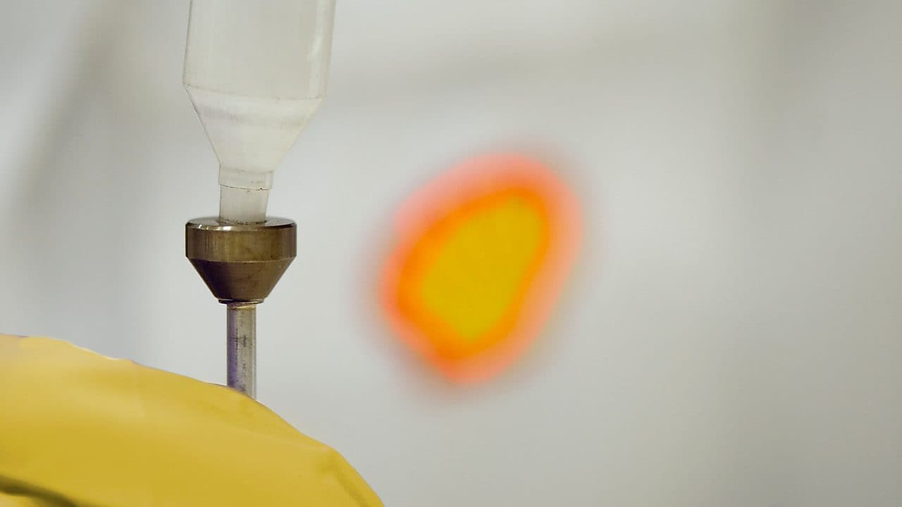 Liquid being poured into a plastic funnel by a shell scientist in a laboratory