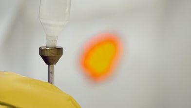 Liquid being poured into a plastic funnel by a shell scientist in a laboratory