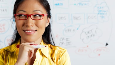 Close up of Asian businesswoman smiling in front of whiteboard