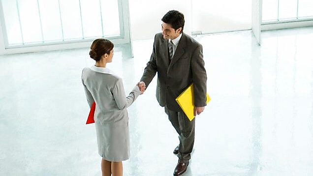 Businessman and businesswoman shaking hands in lobby