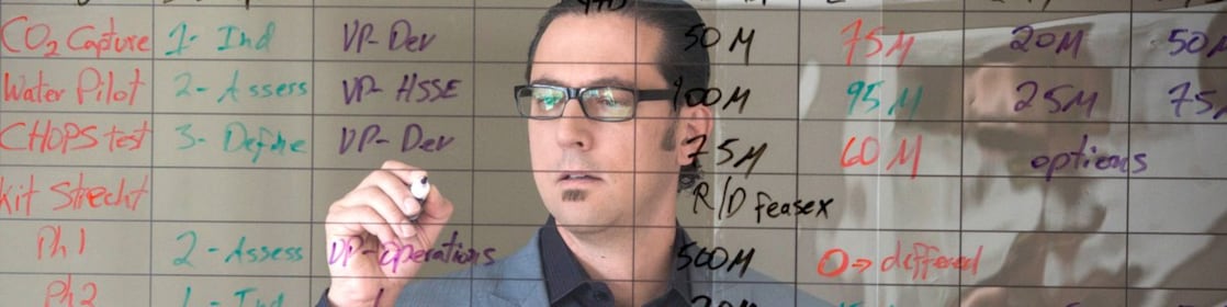 employee writing on transparent board.