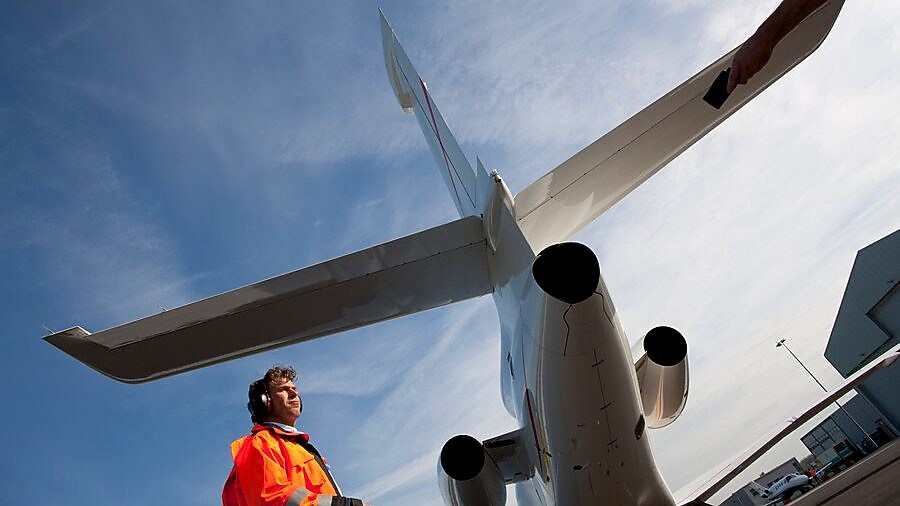 bottom up view of staff walking behind the tail end of a plane