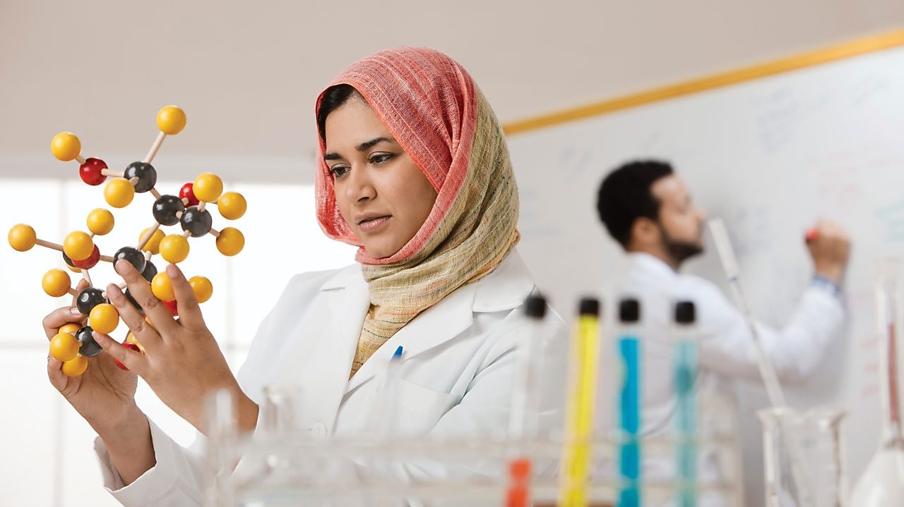 Young female scientist examining a molecular model