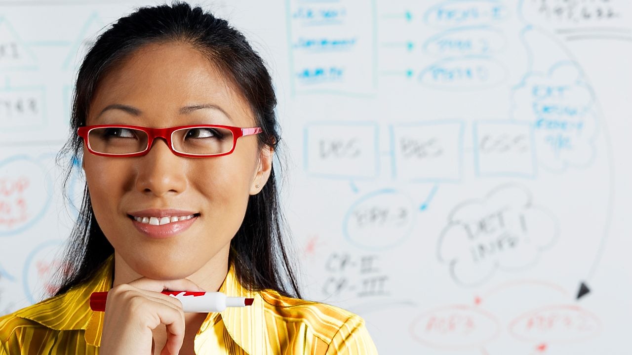 Close up of Asian businesswoman smiling in front of whiteboard