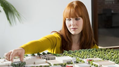 Caucasian businesswoman examining scale model