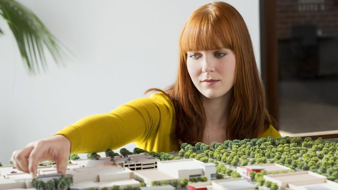 Caucasian businesswoman examining scale model