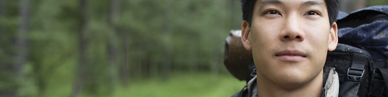 Portrait of Asian male backpacker in the woods