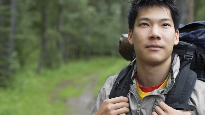 Portrait of Asian male backpacker in the woods