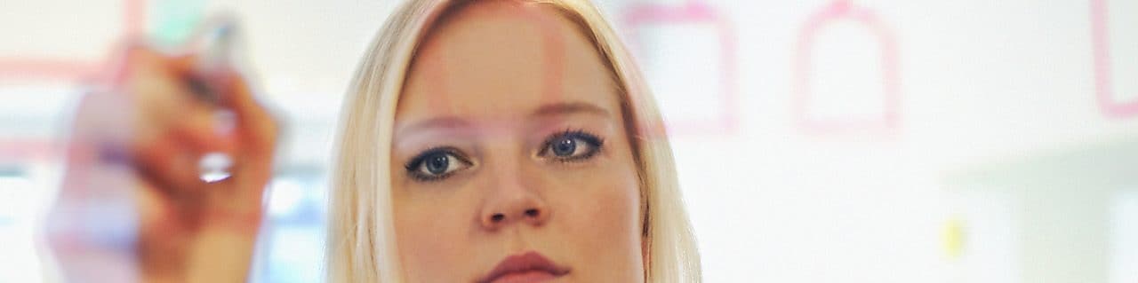 Sweden, Businesswoman writing on glass wall in office