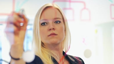 Sweden, Businesswoman writing on glass wall in office