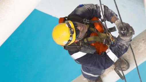 Aerial view of man working in safety gear climbing scaffolding