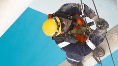 Aerial view of man working in safety gear climbing scaffolding